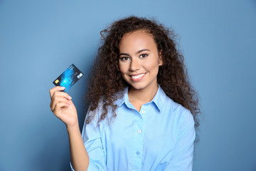 Wall Mural - Attractive woman holding credit card on blue background