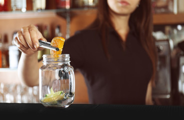 Poster - Woman hands putting fruits into glass jar on bar counter