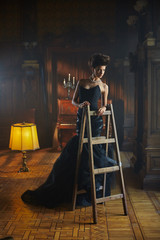 Wall Mural - Aggressive model stands in evening gown on step-ladder