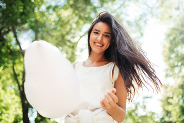 Canvas Print - Bottom view of beautiful young woman smile with cotton candy on nature background.