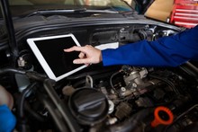 Mechanic Using A Digital Tablet While Servicing Car Engine