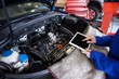 © Wavebreak Media - Mechanic using a digital tablet while servicing car engine
