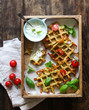 © irinagoleva - Zucchini waffles with fresh tomatoes, basil and yogurt sauce on a wooden background, overhead shot