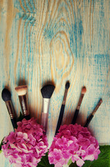 Makeup brushes and hydrangea on the abstract wooden blue backgro