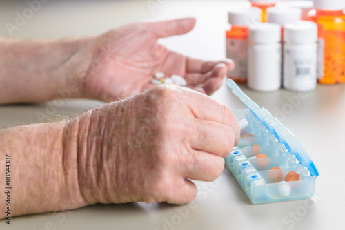 Fotografie, Obraz Elderly man sorting daily medication into a pill box.