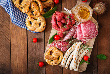 Wall Mural - Glass of beer, pretzels and various sausages on wooden background. Oktoberfest. Top view