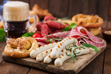 Wall Mural - Glass of beer, pretzels and various sausages on wooden background. Oktoberfest.