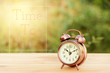 vintage alarm clock on table with blur green background and sunr