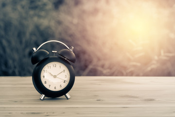 vintage alarm clock on table with blur background and sunray