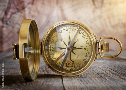 Old compass on the vintage map background. Retro style.