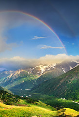 Canvas Print - Rainbow under mountain ridge. Panoramic landscape in the summer time