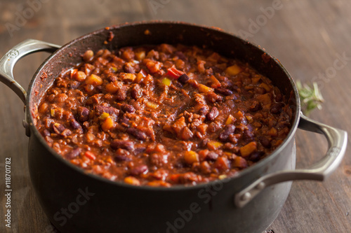 Fotografie, Obraz Organic Vegetarian Chili In Iron Pot Served With Rosemary On Dis