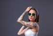 © Africa Studio - Beautiful young woman with tattoo wearing sunglasses and posing on gray background