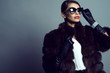 Beautiful glam model wearing white silk blouse, sable coat, leather gloves, sunglasses and set of luxurious bracelet, ring and silver chain with pendant. Natural furs concept. Studio shot. Copy space