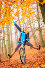 Active woman having fun riding bike in autumn park