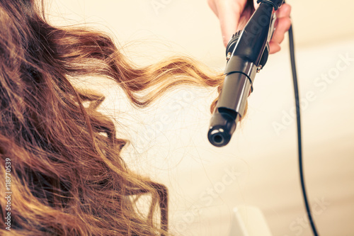 Fotomural Stylist curling hair for young woman.