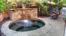 Irvine, CA, USA – August 19, 2016: Oval Hot Tub Spa With Waterfall And Feng Shui Garden Decor Located In A Private Small Patio With Plants And Flowers.