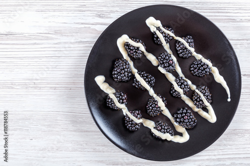Fotografia, Obraz Fresh organic blackberries on black plate, top view