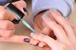 © juliko77 - Nail salon - Applying green nail polish on female fingers.