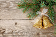 Christmas bells and spruce branches on wooden background