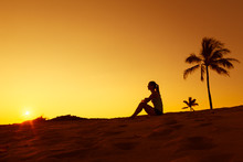 Young Woman Relaxing On A Tropical Beach Watching The Sunset. 