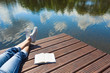 © kieferpix - Relaxing and vacation and reading concept. Woman relaxing by the waters edge with a book by her side.