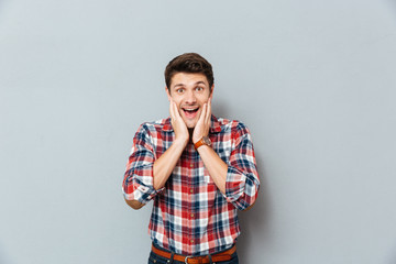 Wall Mural - Surprised excited man in plaid shirt standing with mouth opened