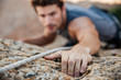 Man reaching for a grip while he rock climbs