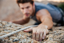 Man Reaching For A Grip While He Rock Climbs