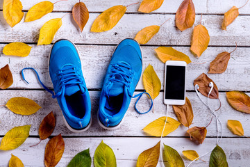 Wall Mural - sports shoes. smartphone, earphones, autumn leaves. white wooden