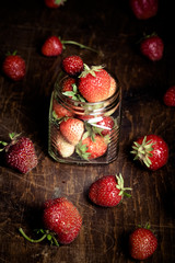 Lots of fresh bright red strawberries and glass jar. Selective f