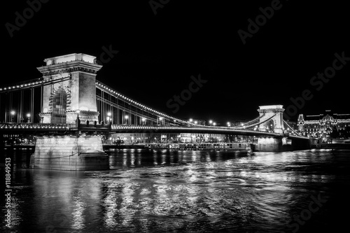 A black and white perspective on the historic Chain Bridge in Budapest at night reflecting in the Danube River Poster