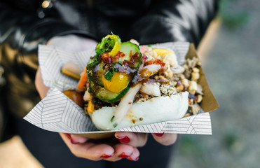 Close up photo of a traditional Vietnamese banh bao steamed bun with pork filling at a street food market. Selective focus.