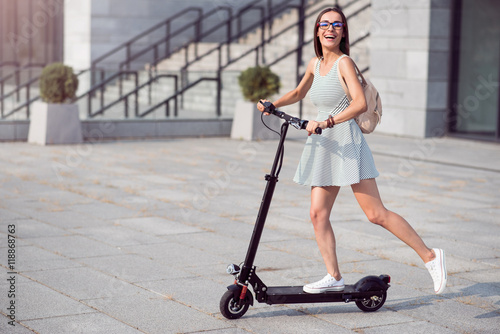 Fotografía Joyful woman riding a kick scooter