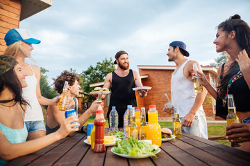 Joyful young people eating and drinking at the table outdoors