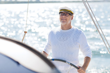 Canvas Print - senior man at helm on boat or yacht sailing in sea