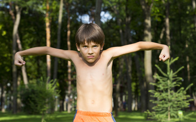 portrait of a boy in nature which shows his muscles