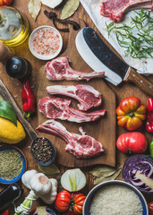 Wall Mural - Ingredients for cooking dinner. Raw uncooked lamb meat ribs, rice, oil, spices and vegetables over wooden background, top view, vertical composition