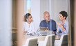 © nakophotography - Group of business people in discussions in modern office building conference room shot from outside the room through the glass walls.