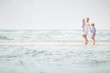 © goodmoments - Young mother in white dress walking with her two little boys along the ocean beach. Woman with baby and boy enjoying vacation by the sea. On the empty beach. Motherhood. Water background. copy space.