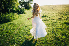 Young Girl In A White Dress In The Meadow. Woman In A Beautiful Long Dress Posing In The Garden. Stunning Bride In A Wedding Dress
