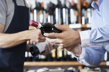 Midsection Of Customer And Salesman With Wine Bottles