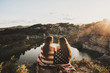 © Robert Marcillas/ADDICTIVE STOCK - Back view of girlfriends in american flag sitting on edge against of lake