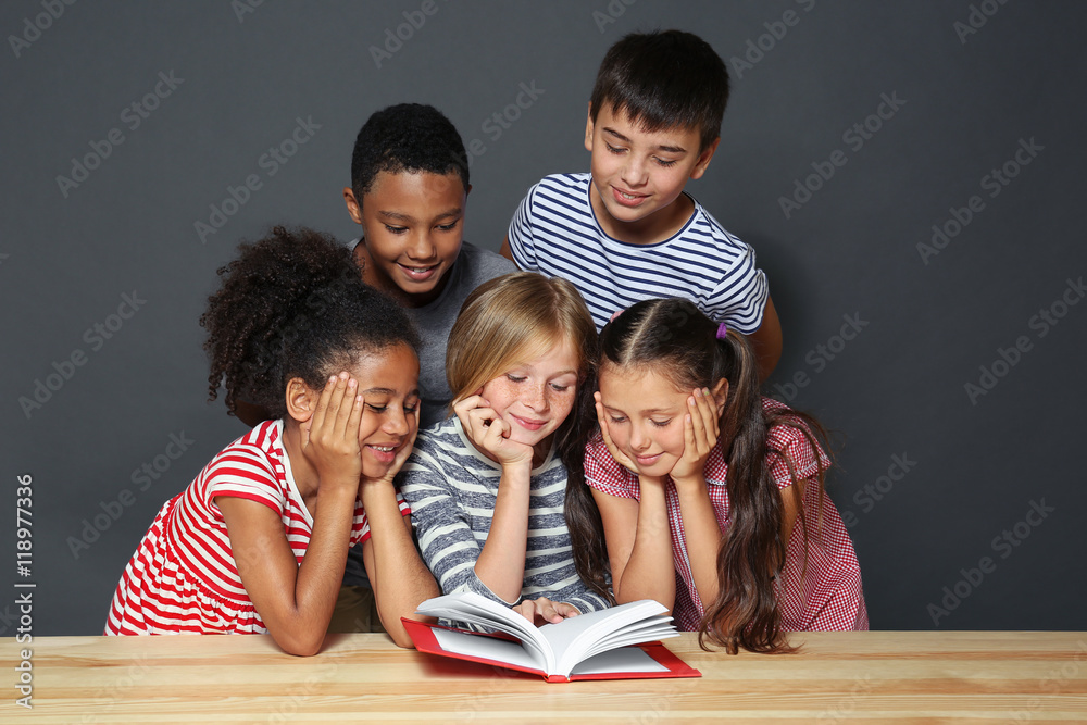 Cute kids reading book on grey background