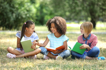 Wall Mural - Cute kids reading books on green grass