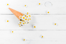 Daisy Flowers In The Ice Cream Cone On White Wooden Background, Flat Lay, Top View