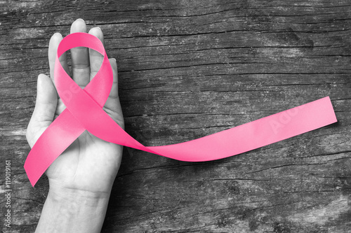 Fotografie, Obraz Pink ribbon awareness symbol on woman hand: Symbolic logo icon concept raising a