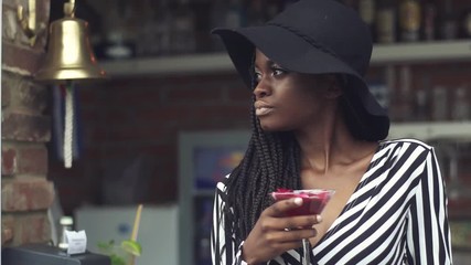 Wall Mural - Gorgeous african american business lady drinking cocktail at bar with fancy interior