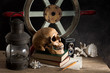 skull with lantern, old book, camera and boat steering on old wood table