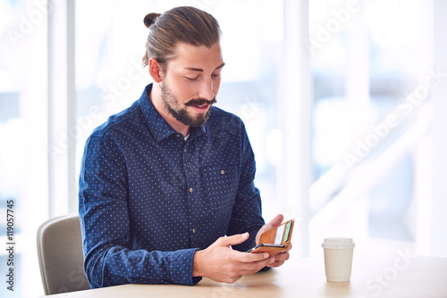 Trendy Handsome Man With Long Hair Tied Back In A Bun Busy Using